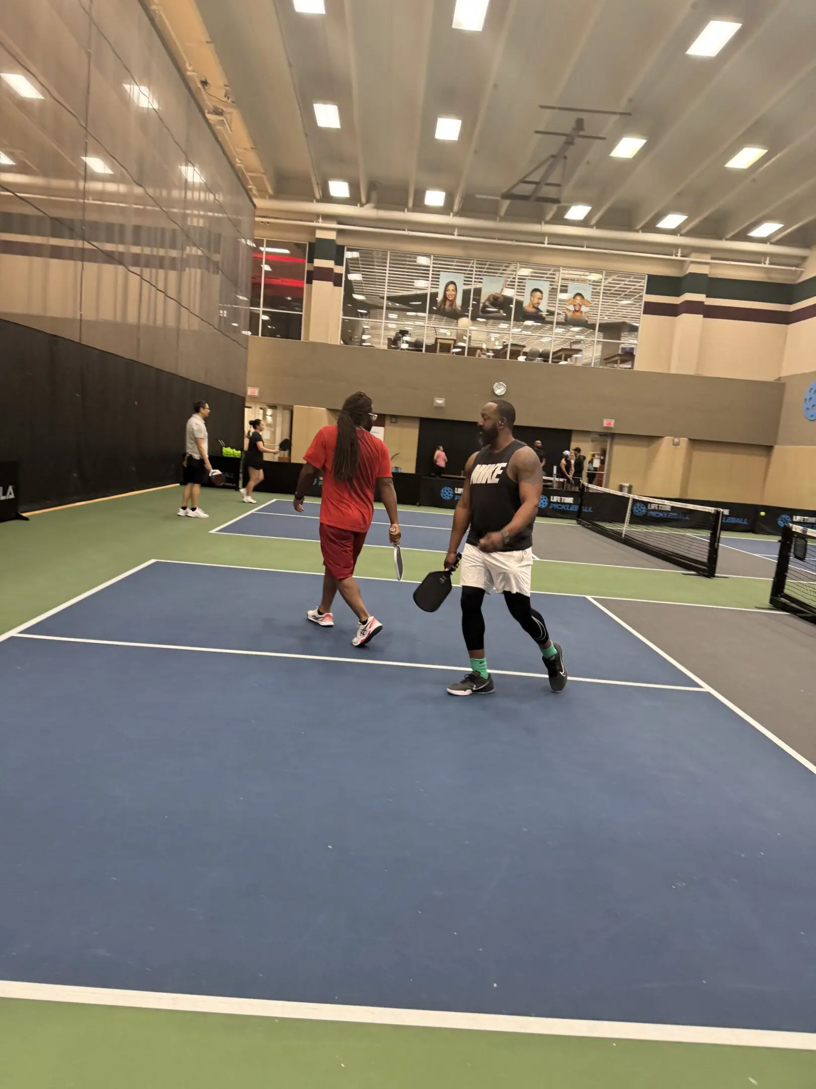Two people playing tennis on a court with the net in front of them.