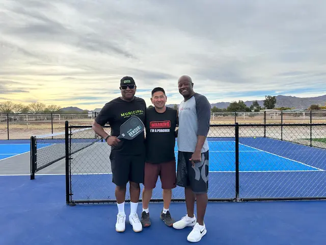 IMG_1537 Three men standing on a tennis court holding rackets.