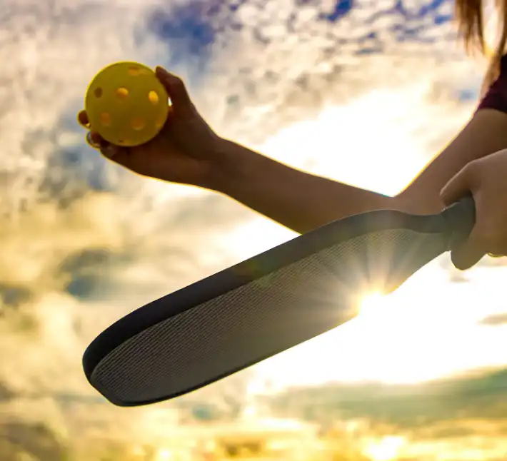 A person holding a tennis ball and racket in their hands.